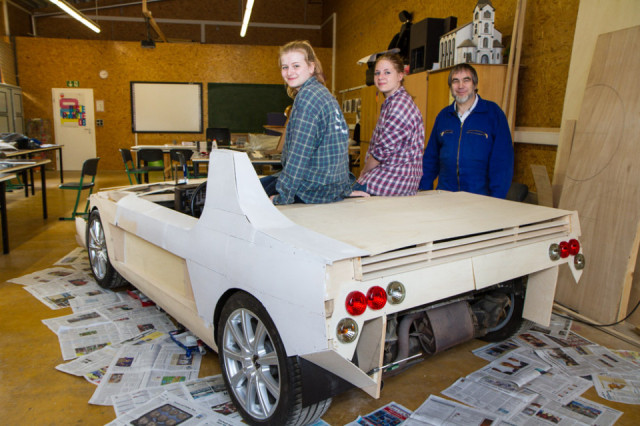 Juliane Richter, Laurina Bergfeld und Kunstlehrer Georg Fuhs (v.l.) mit dem fahrtüchtigen Sportwagen aus Holz. Foto: SMMP/Bock